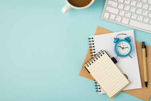 Top view photo of white keyboard cup reminders pen and blue alarm clock on isolated pastel blue background with copyspace