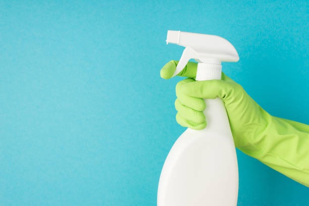 istock Profile photo of hand in green rubber glove using atomizer white detergent spray bottle without label on isolated pastel blue background with copyspace 1321954924