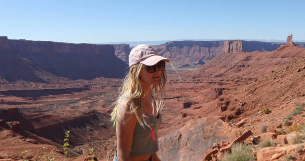 istock Young woman hikes up sunny mountain ridge 1321955363