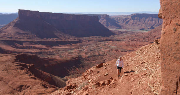 istock Woman hikes up sunny mountain ridge 1321955409