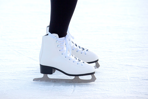legs of a woman in white skates on an ice rink. hobbies and leisure. winter sports