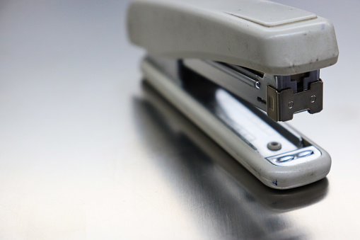 A stapler is a mechanical device that joins pages of paper or similar material by driving a thin metal staple through the sheets and folding the ends