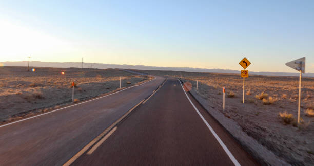 vue panoramique sur la route du désert au lever du soleil - direction arrow sign road sign escape photos et images de collection
