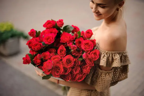 Photo of Great view of bright bouquet of red fresh roses in hands of young woman