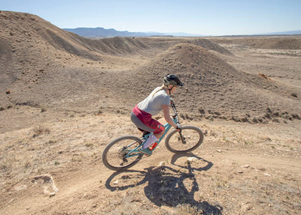 istock Female mountain biker descends desert trail 1321982808