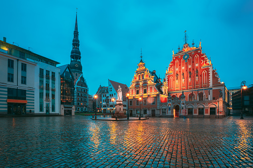 Riga, Latvia. Scenic Town Hall Square With St. Peter's Church, Schwabe House, House Of Blackheads During Night Rain. Popular Showplace With Famous Landmarks On It In Bright Evening Illumination In Summer Twilight Under Blue Sky. Riga, Latvia. Scenic Town