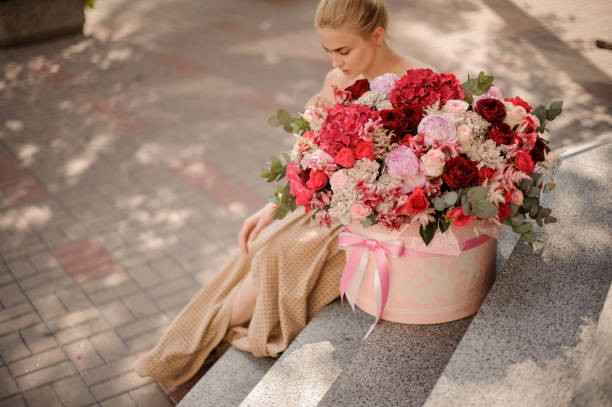 beautiful round box tied with ribbon with flower arrangement on steps beautiful round box tied with ribbon with flower arrangement on steps and young woman nearby hyacinth red stock pictures, royalty-free photos & images