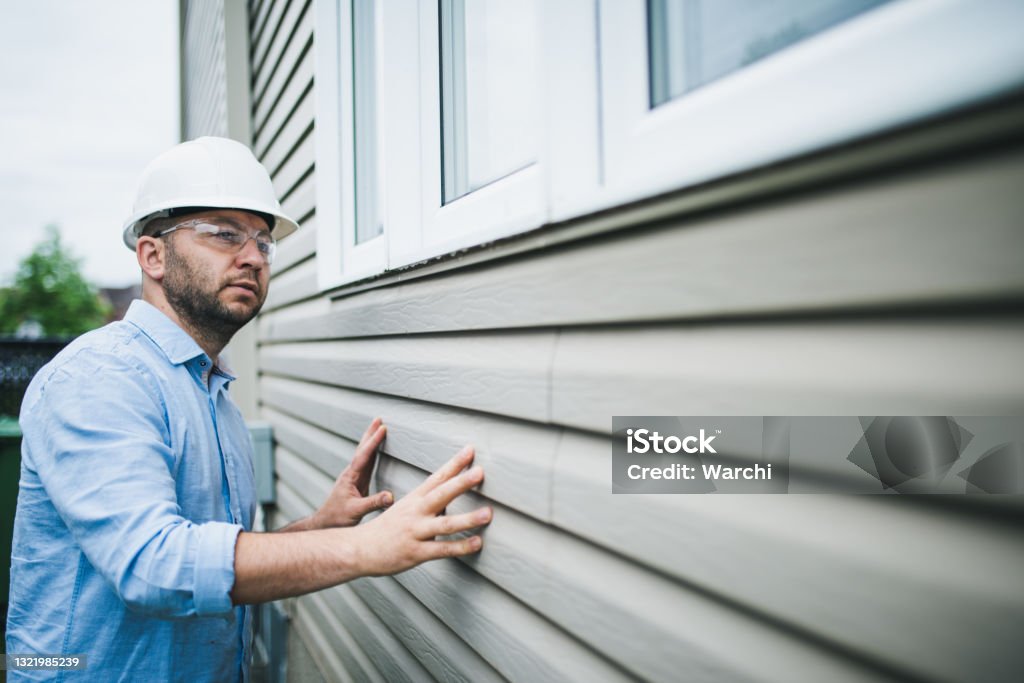 Building inspector checking the windows of a residential building Building inspector at work. He is inspecting the windows of a residential building. Siding - Building Feature Stock Photo