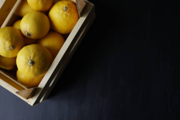 Istanbul, Turkey-May 4, 2021: A case of lemons on a black wooden background. Full Frame, Still life, Flat lay. Shot with Canon EOS R5.