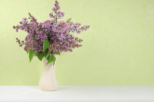 istock Home interior with decor elements, beautiful spring branches of lilacs in a vase on a light background, abstract flower arrangement, still life with place for text, floral birthday card, wedding, 1321991383