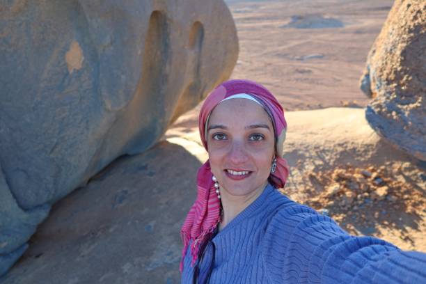istock A cheerful young woman wearing a purple pullover and a head cover  with hazel eyes taking a selfie in the middle of the rocks of the blue desert in Egypt 1321994006