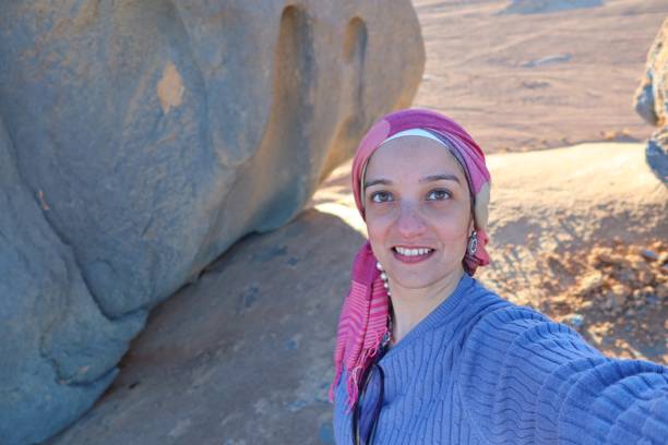 istock A cheerful young woman wearing a purple pullover and a head cover  with hazel eyes taking a selfie in the middle of the rocks of the blue desert in Egypt 1321994029