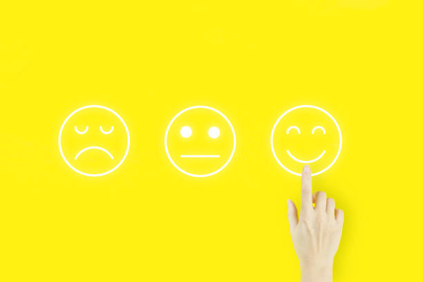 istock Customer service evaluation and satisfaction survey concepts. Young woman's hand finger pointing with hologram face emotion on yellow background. 1321994131