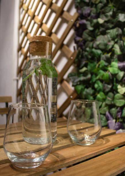 istock Two empty glasses and  a rustic bottle with water and mint, fabric wall leaves and wooden grille in the background; docoration ideas 1322004489