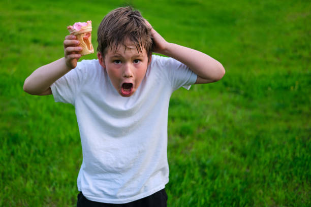 Shocked boy with empty ice cream cup, cheating with food Shocked boy with empty ice cream cup, cheating with food stealing ice cream stock pictures, royalty-free photos & images