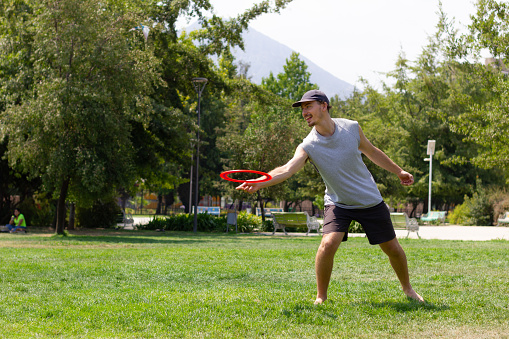 Handsome Man is Throwing a Frisbee and Enjoying in Summer Day with Friends.