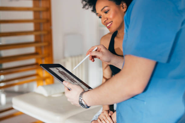 photo en gros plan d’un médecin utilisant une tablette numérique lors d’une consultation avec un patient souriant - doctor digital display digital tablet healthcare and medicine photos et images de collection