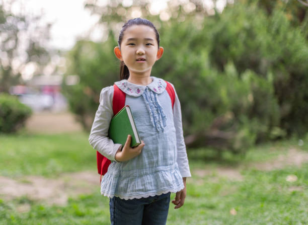 istock Little Girl Holding Book 1322018372