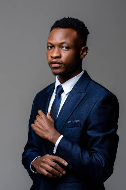 istock Young handsome African man wearing formal business suit looking at camera isolated on studio gray background 1322018972