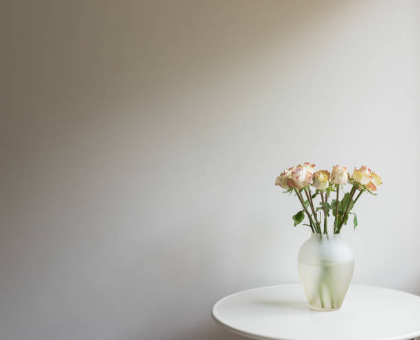 istock Cream and pink roses on table against beige wall 1322038520