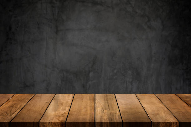 istock Wooden table top with dark concrete polished wall blurred background. Copy space for your display or montage product design. 1322040667