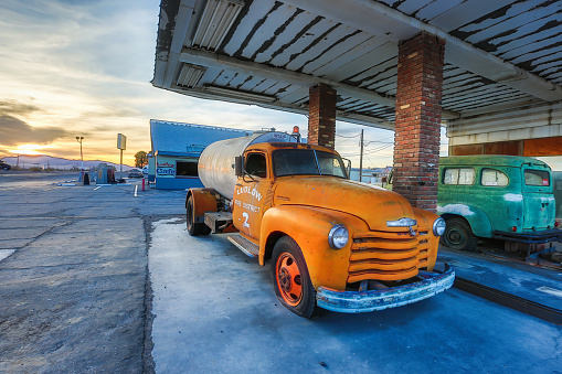 Ludlow, California - May 04, 2014:  Like so many other towns along Route 66, Ludlow has seen economic downturns since the advent of the Interstate highway system.   Today, most people who pass by, come to explore it as a ghost town.   The two abandoned trucks in the photo are parked permanently on an abandoned gas station.  On either side of this abandoned gas station are two establishments that were still in operation at the time of this photo.   One is the Ludlow Cafe and the other is the Ludlow Inn.  The orange truck appears to have been part of the Ludlow Fire Department while the purpose of the green truck is not determinable.   Route 66 runs directly in front of these establishments.