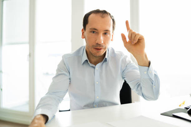 istock Man Raising Hand In Video Conference Call 1322050299