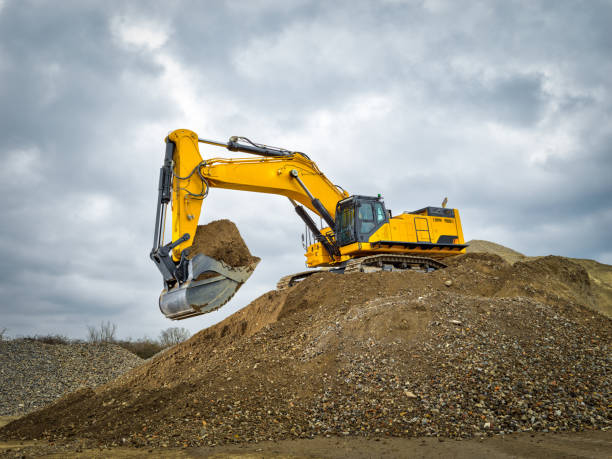 excavatrice ciel bleu chantier de construction de machines lourdes - trop lourd photos et images de collection