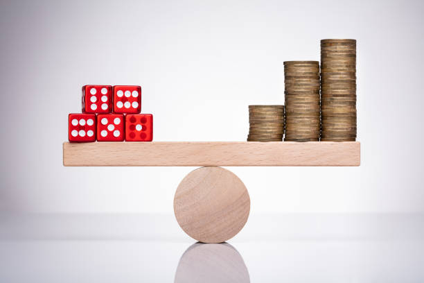 istock Dice And Stack Of Coins On Seesaw 1322052183