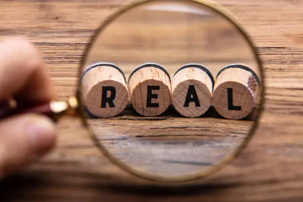 Photo of Hand Holding Magnifying Glass In Front Of Real Text