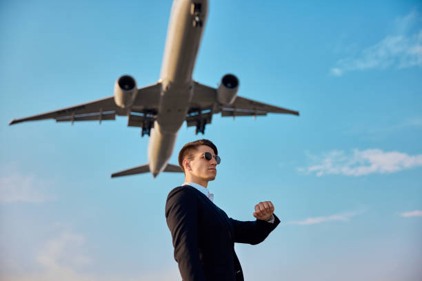 istock Businessman against sky with landing airplane. 1322054688