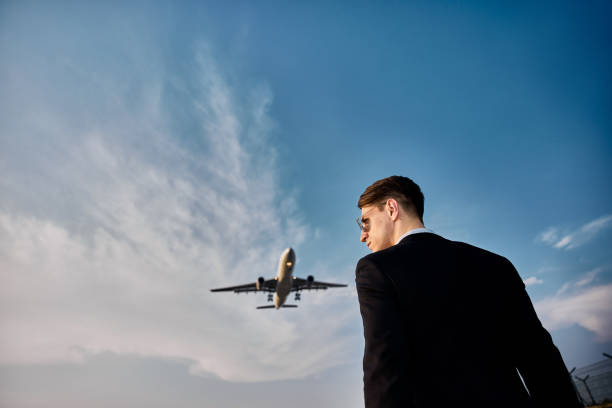 istock Businessman against sky with landing airplane. 1322054690
