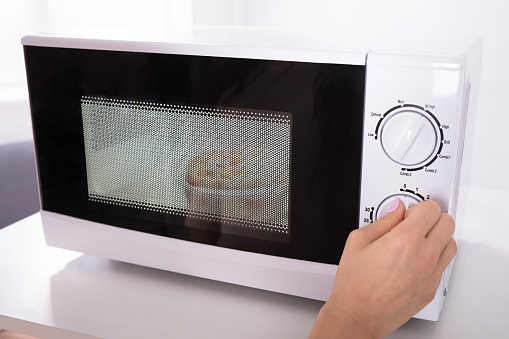 Close-up Of A Woman's Hand Using Microwave Oven For Preparing Food