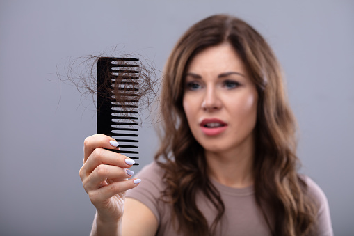 Close-up Of A Worried Woman Holding Comb Suffering From Hairloss
