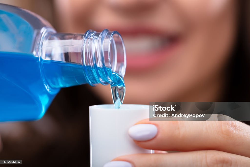 Woman Pouring Mouthwash Into Cap Close-up Of A Woman's Hand Pouring Mouthwash Into Cap Mouthwash Stock Photo