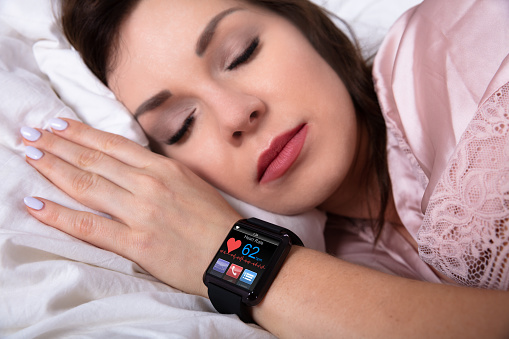 Beautiful Woman Sleeping On Bed With Smartwatch Showing Heartbeat Rate