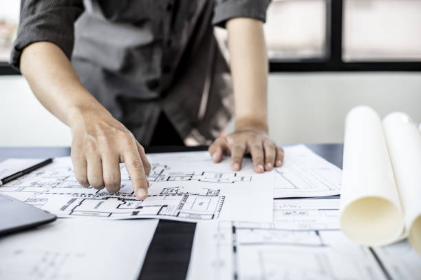 istock The architect is pointing to the house plans he has designed, he is meeting with engineers and clients to adjust the design before construction starts. Floor plan and interior design concepts. 1322062349