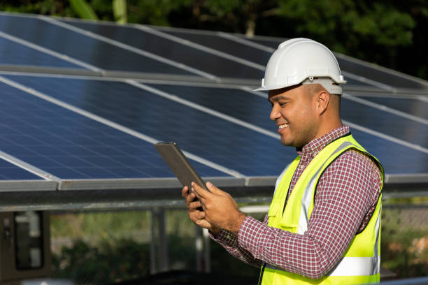 istock Young asian electrical engineer standing in front of Solar cell panels farm. He using tablet to checking the system. Solar generator power concept. 1322064908