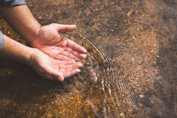 istock Closeup water drops falling down from man hand at river in mountains.Hand touching fresh water. 1322066689