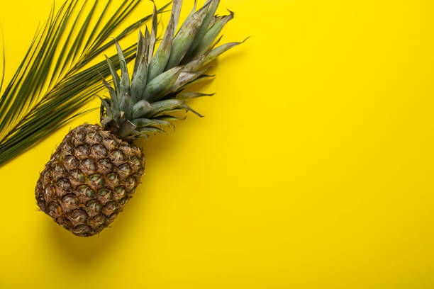 istock fresh ripe whole yellow pineapple and lsit palms on a yellow background. Top view, flat lay 1322066933