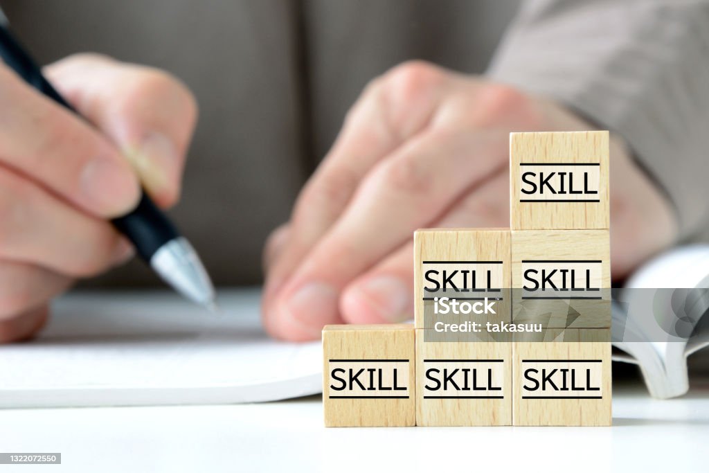 Skills up concepts, piled wooden blocks with skill word and studying person Educational Exam Stock Photo