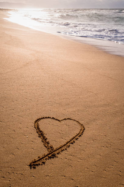 istock Heart shape written in the sand with wave washing in 1322073642