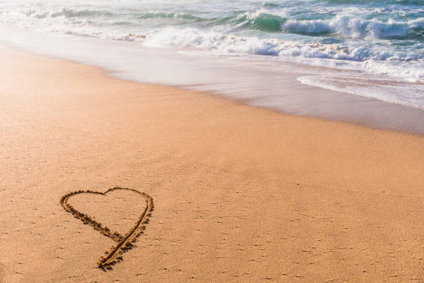 istock Heart shope written in the sand with wave washing in 1322073688