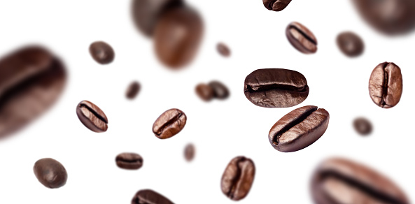Brown roasted coffee beans flying on background.