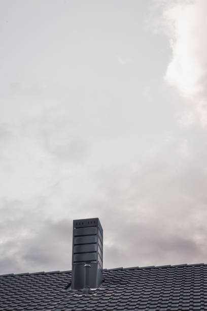 Chimney on roof with tiles and cloudy sky