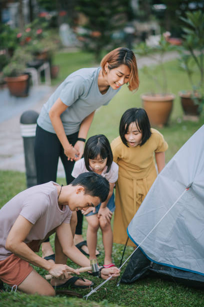 asian chinese father setting up camping tent with help from his family at backyard of his house during weekend asian chinese father setting up camping tent with help from his family at backyard of his house during weekend hit the nail on the head stock pictures, royalty-free photos & images