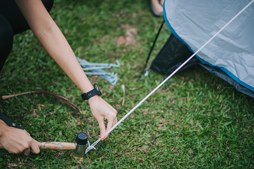 asian chinese mother setting up camping tent with hammer and tent peg at backyard of her house