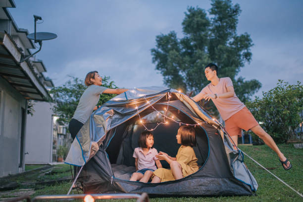 famiglia cinese asiatica che mette su una luce di corda decorando il campeggio nel cortile delle loro attività del fine settimana di soggiorno in casa - malaysian person family asian ethnicity mother foto e immagini stock