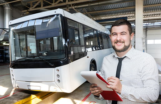 Serviceman with notepad on the background of the bus in the garage