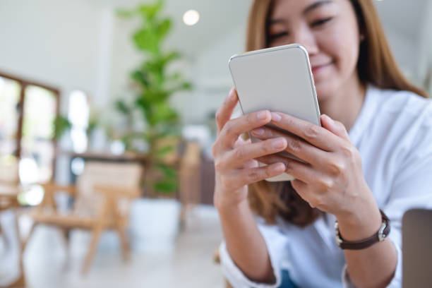 istock a beautiful young asian woman holding and using mobile phone 1322083989